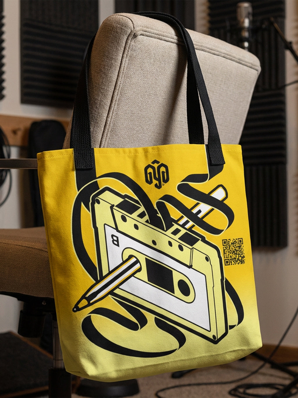 Tote bag amarilla con diseño de cassette y pluma Bic rebobinando cinta; efecto 3D con la cinta alineada a las asas.