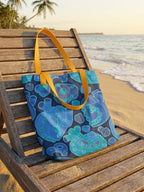 Bolsa tote bag colección “Mecanismos Afectivos” con patrón de corazones mecánicos isométricos, sobre camastro de playa.