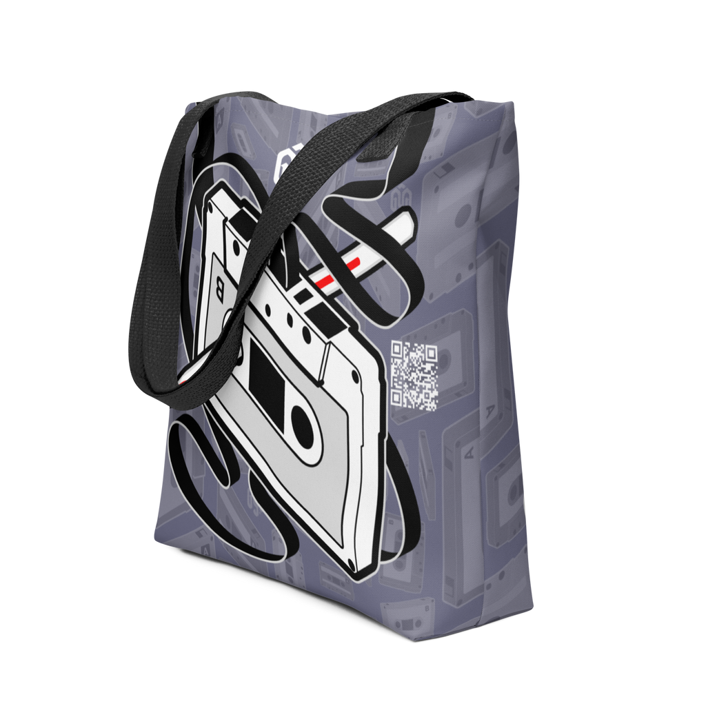 Vista general de tote bag gris con cassette lado B y pluma Bic rebobinando cinta; efecto 3D con cinta alineada a las asas.
