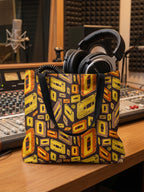 Tote bag con estampado de cassettes en tonos marrones y amarillos en un estudio de grabación.